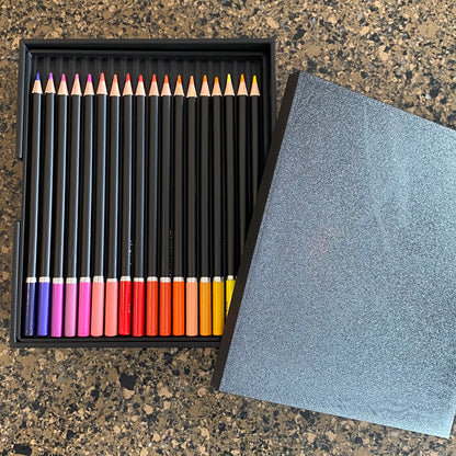 A black colored pencil caddy with multiple colored pencils visible, placed next to a gray lid or cover.