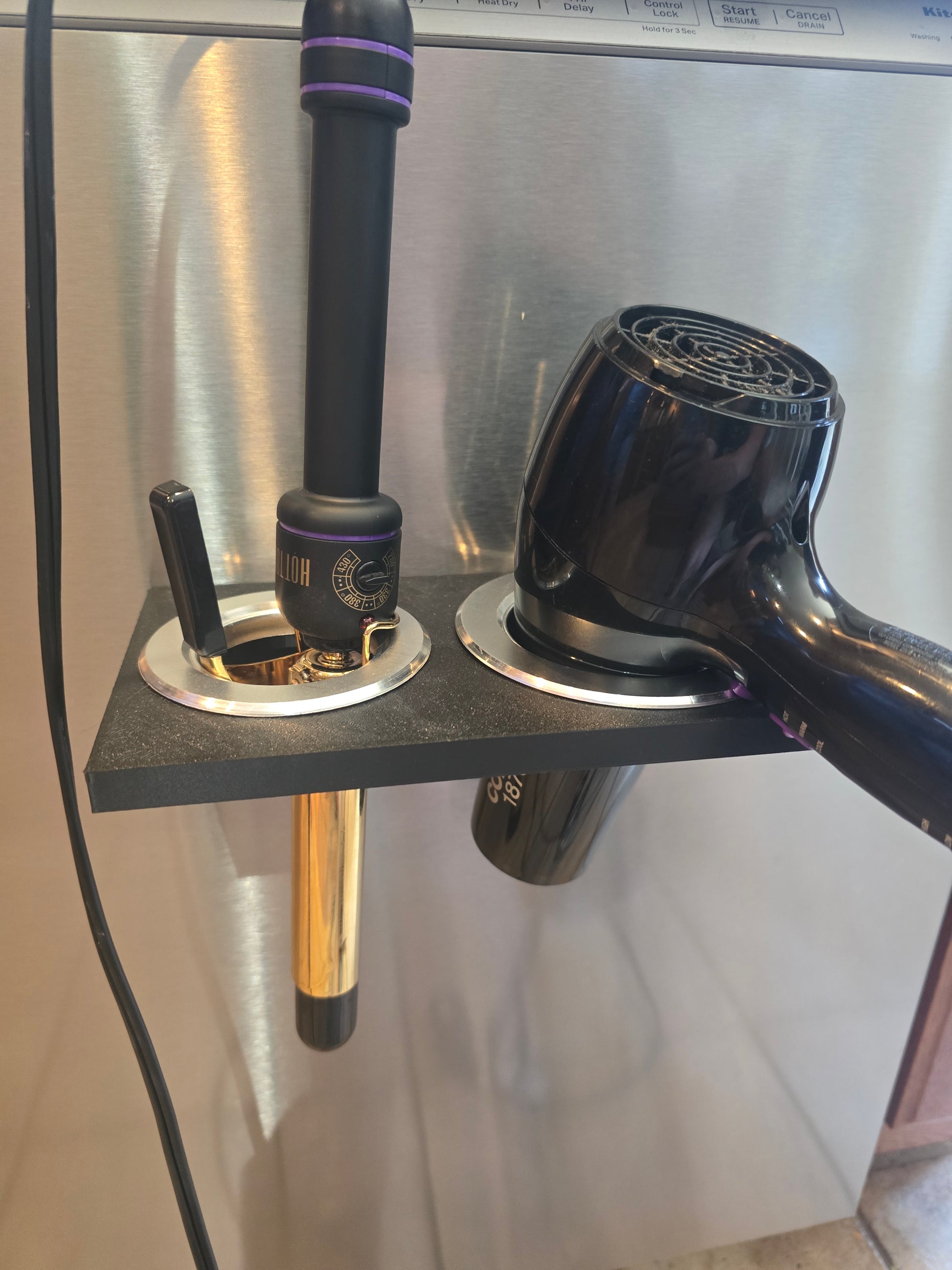 Black hair dryer and curling iron holder mounted on metal surface, magnetic mount